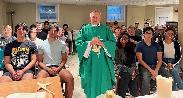 Father Carlos Castilla poses for a photo with Monmouth University students following the Mass he celebrated on Sept. 8. Courtesy photo