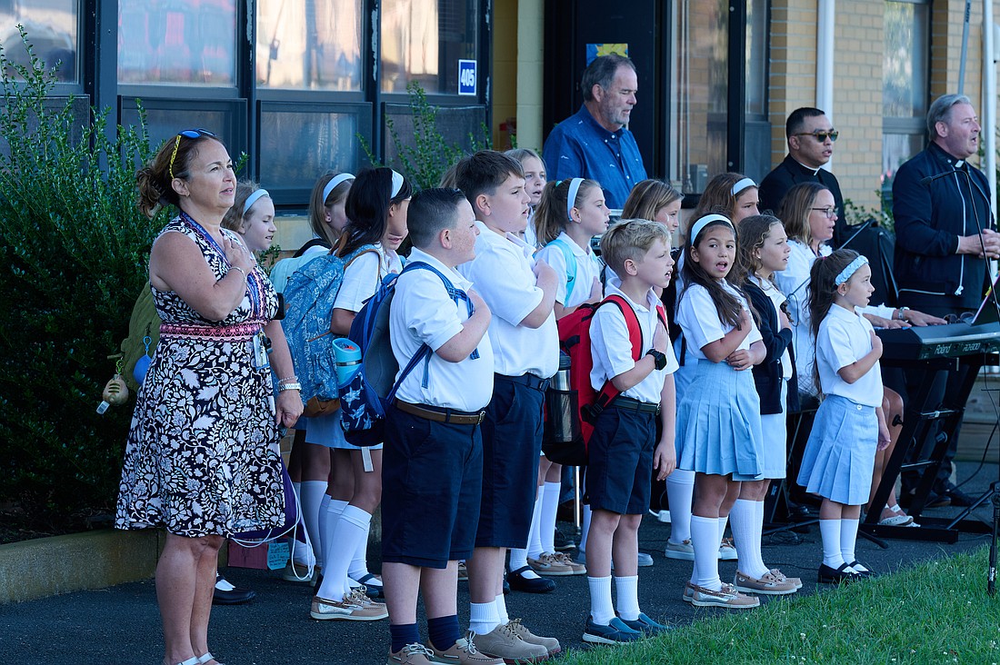 A Sept. 3 prayer service on school grounds opened the academic year for St. Catharine School, Spring Lake. The Pledge of Allegiance is led, from left, by principal Donna White, students, St Catharine-St. Margaret Parish music director Billy Lawlor, parochial vicar Father Gregg Abadilla, and Father Damian McElroy, pastor.  Mike Ehrmann photo