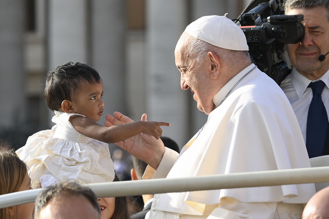 Pope Francis greets a young child as he rides in the popemobile around St. Peter's Square at the Vatican before his weekly general audience Sept. 18, 2024. (CNS photo/Vatican Media)