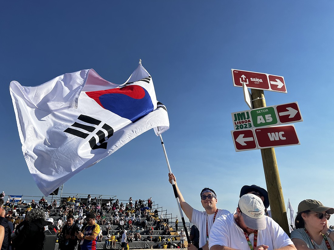 A young man from South Korea waves his country's flag before Pope Francis arrives for the closing Mass of World Youth Day at Tejo Park in Lisbon, Portugal, Aug. 6, 2023. At the end of Mass, the pope announced the next WYD will be held in Seoul, South Korea, in 2027. (CNS photo/Lola Gomez)