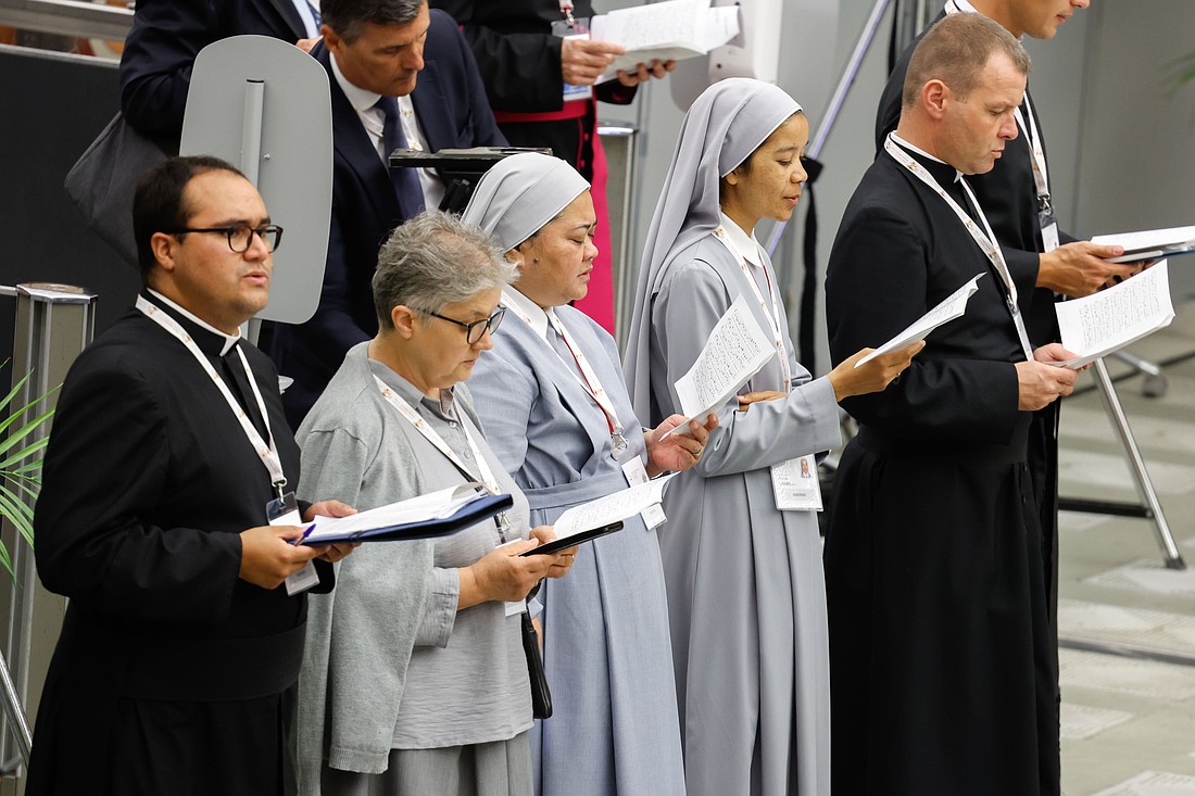 A choir leads members of the Synod of Bishops in prayer as they gather in the Paul VI Audience Hall at the Vatican before the opening session Oct. 2, 2024. (CNS photo/Lola Gomez)