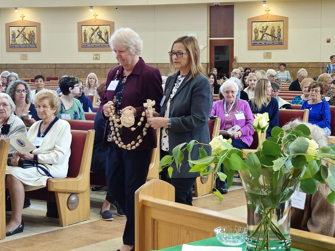 Before the Mass, Rosarian representatives from the various parishes participated in a procession in honor to the Virgin Mary. Carrying the Rosary in this photo are Rita Carnival of Mary, Mother of the Church Parish, Bordentown, left, and Sandra Estrada of Our Lady of the Angels Parish, Trenton. Mary Stadnyk photo