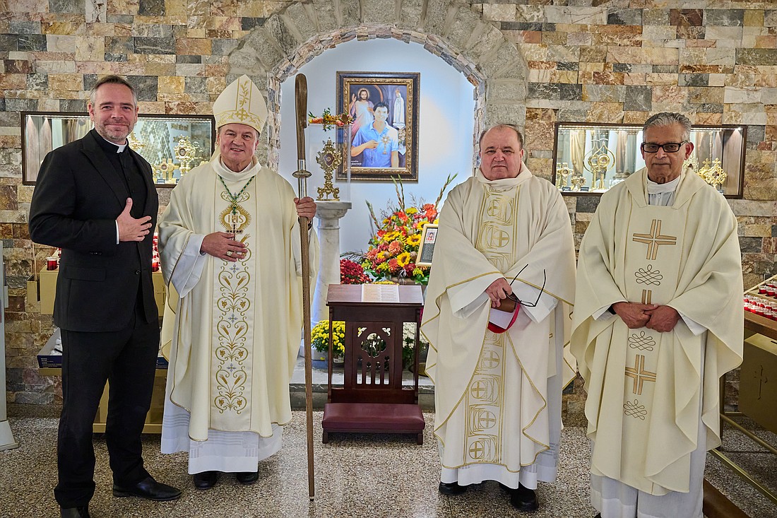 Bishop Krzysztof Jozef Nykiel, regent of the Apostolic Penitentiary in Vatican City, visits the shrine dedicated to Blessed Carlo Acutis that's located in the gathering space of St. Dominic Church, Brick. Before celebrating Mass in the parish church on Oct. 12, he is greeted by priests, Father Brian Woodrow, pastor, on left, and parochial vicars, Father Marian Kokorzycki and Father Joseph Gnarackatt. Mike Ehrmann photo