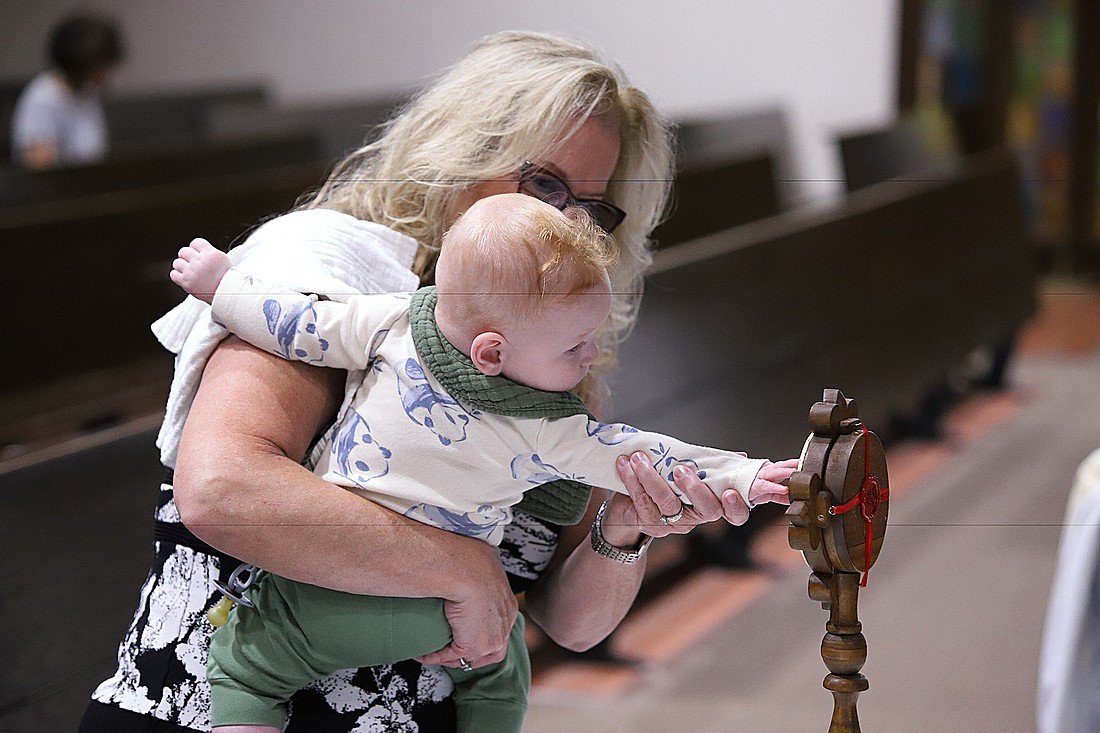 A baby has the opportunity to touch one of the relics of St. Padre Pio of Pietrelcina as they are displayed in St. Ann Parish, Keansburg. John Batkowski photo