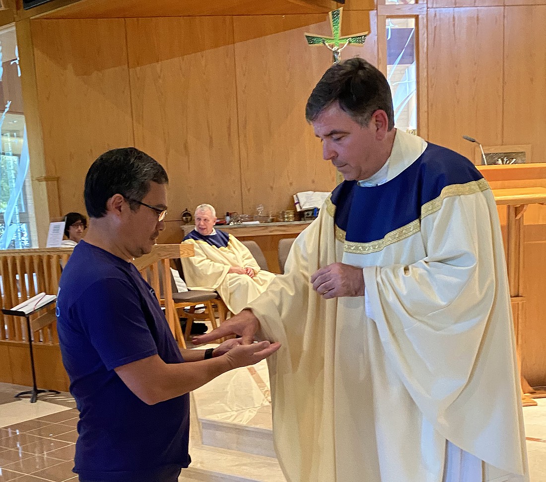 Father John Bambrick, pastor of St. Aloysius Parish, Jackson, one of the priest concelebrants at the annual White Mass, blesses the hands of a medical professional. Kayla Laterndresse photo