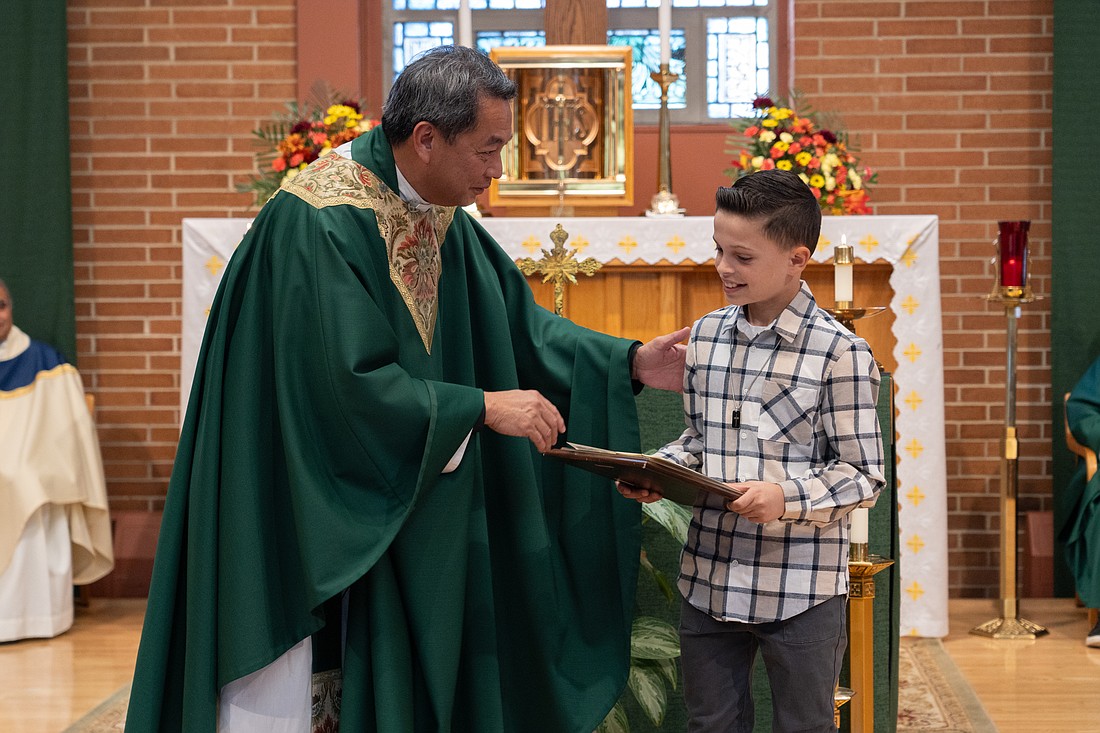 Father Peter James Alindogan, pastor of St. Veronica Parish, Howell, and director of the diocesan Missions Office, congratulates Frankie Picciolo, who was named a national winner in the Christmas Artwork Contest sponsored by the Missionary Childhood Association. Matt Marzorati photo