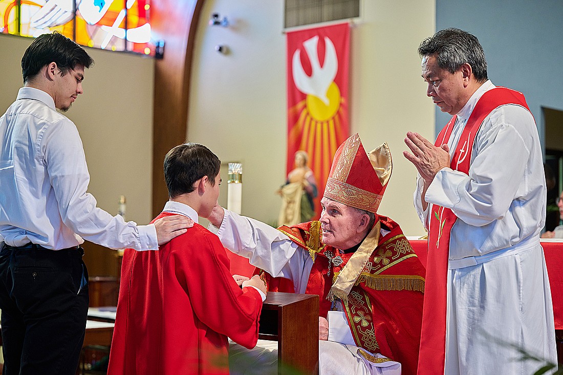 Bishop David M. O'Connell, C.M., confirms young people in St. Veronica Parish, Howell, in May. At right is Father Peter James Alindogan, St. Veronica pastor. Mike Ehrmann photo