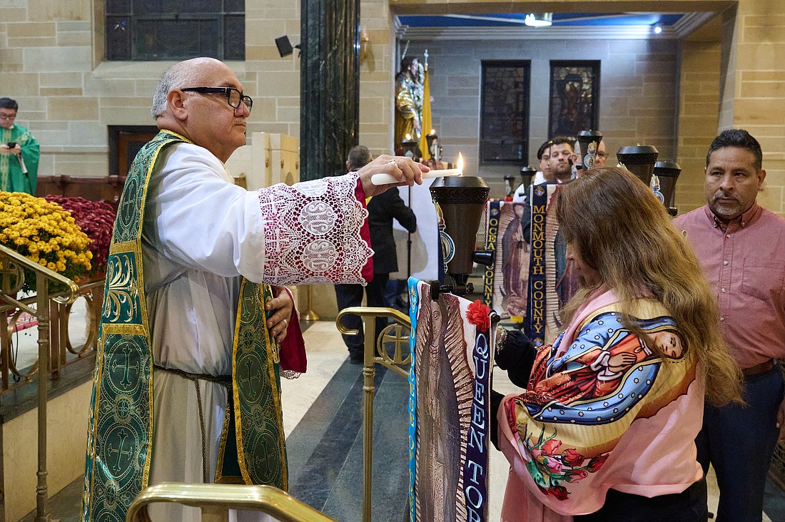 Msgr. Joseph Roldan, Cathedral rector, lights a torch held by a team captain during an Oct. 26 Mass. The Torches will be traveling to schools and parishes in the Diocese in November. Mike Ehrmann photos