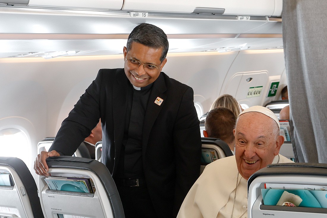 Cardinal-designate George Koovakad, the Vatican official responsible for organizing papal trips, stands next to Pope Francis for a news conference aboard his flight back to Rome Sept. 29, 2024, after visiting Luxembourg and Belgium during his 46th international trip. (CNS photo/Lola Gomez)