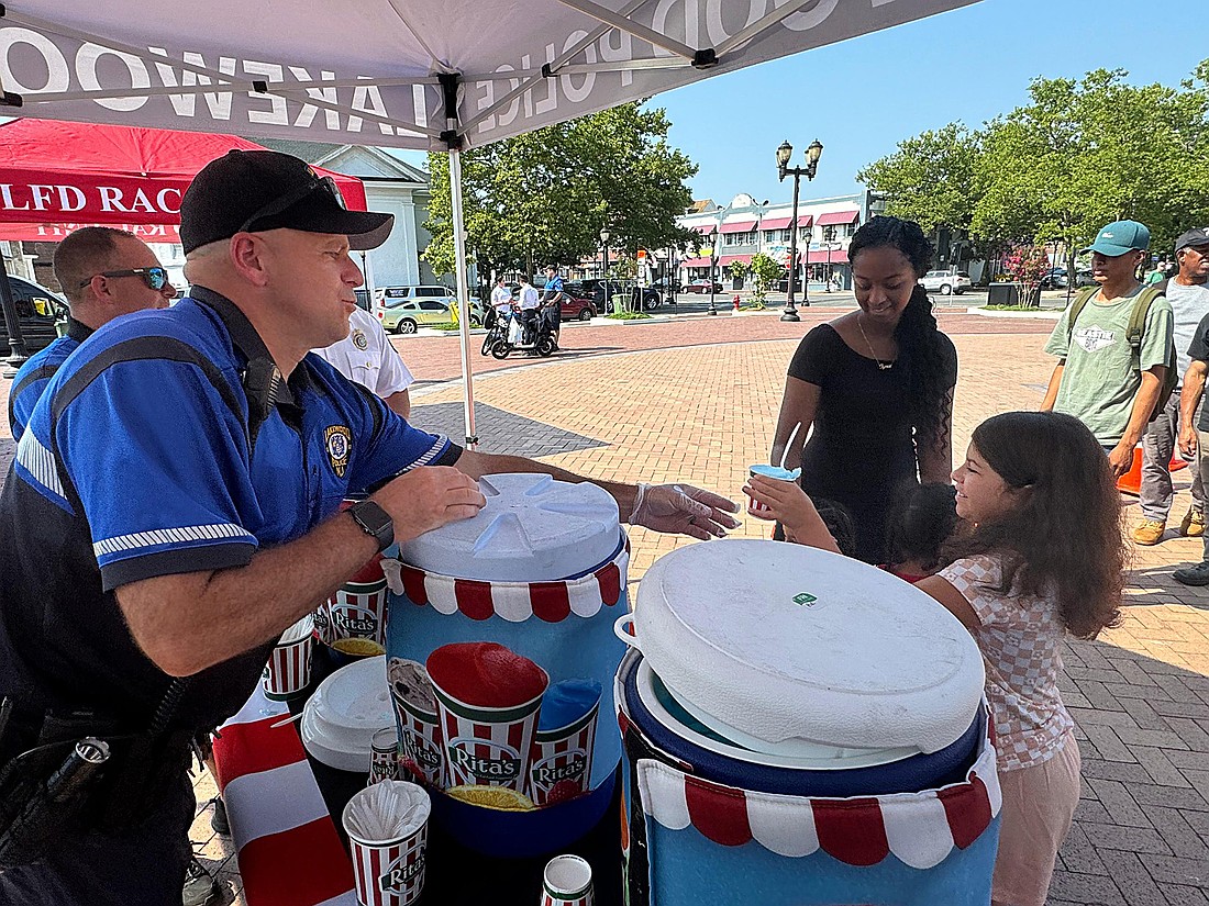 Lakewood Community Coalition member, Officer Jason Yahr, hands a Rita’s Italian Ice to a Lake-wood resident at the coalition’s “Chill with a Cop” event. Courtesy photo