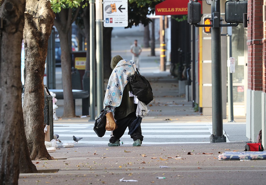 In what has become a familiar sight in many cities, a person facing homelessness carries all of his belongings as he walks along a street in San Francisco. OSV News photo/Bob Roller