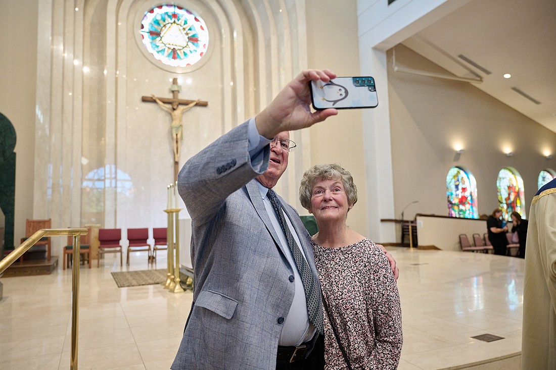 An anniversary couple takes a selfie with the sanctuary backdrop of St. Robert Bellarmine Co-Cathedral, Freehold.