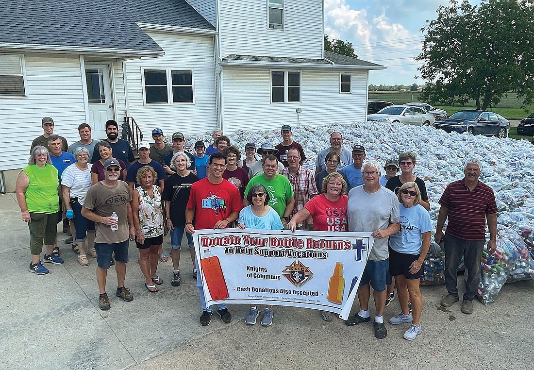 Members of the Knights of Columbus and family members from Msgr. Esper Council 3027 in Fowler, Mich., gather near 131,000 bottles and cans collected during the council’s annual Returns for Vocations fundraiser. The donated recyclables and additional cash contributions yielded $14,500 to support men and women in the Diocese of Lansing who are discerning the priesthood or religious life. (OSV News photo/Knights of Columbus)