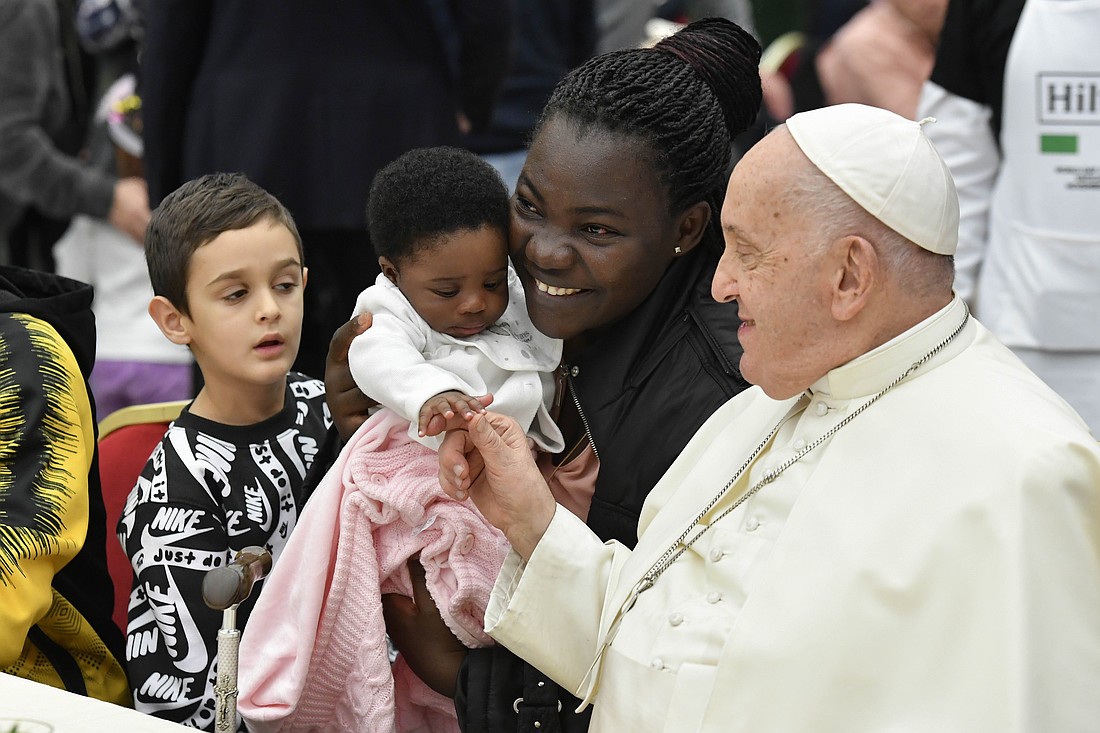 Pope Francis greets a woman and child during a lunch in the Vatican audience hall Nov. 19, 2023, the World Day of the Poor. (CNS photo/Vatican Media)