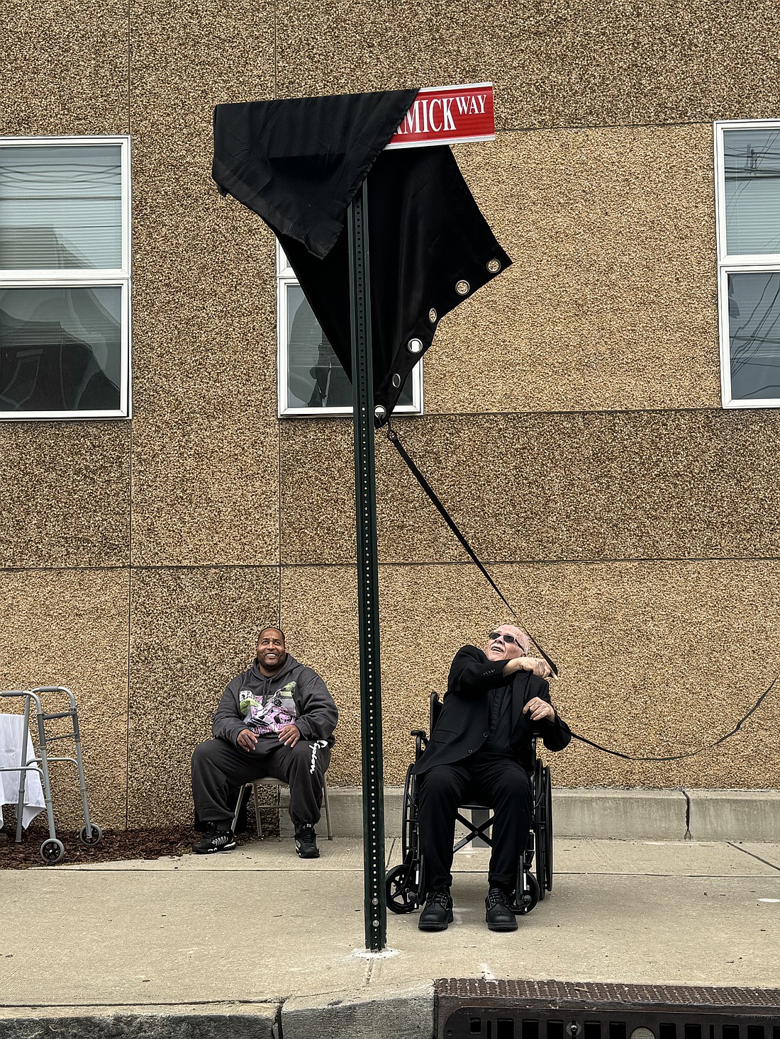 Father McCormick proceeds to unveil the cloth covering the new street sign.