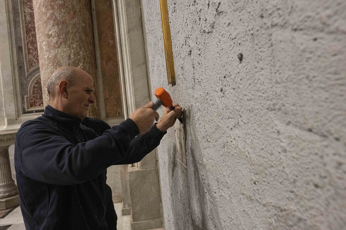 A worker uses a chisel to remove a box that had been cemented into the Holy Door at the basilica at the end of the Jubilee of Mercy in 2016 during a ceremony in the basilica Dec. 2, 2024. The box was removed in preparation for Pope Francis opening the Holy Door Dec. 24. (CNS photo/Vatican Media)