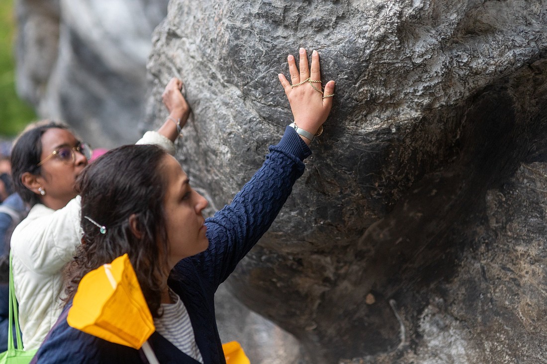 Pilgrims touch the rock at the Grotto of the Apparitions in the Sanctuary of Our Lady of Lourdes, France, on Aug. 14, 2024. (OSV News photo/courtesy Lourdes Sanctuary)