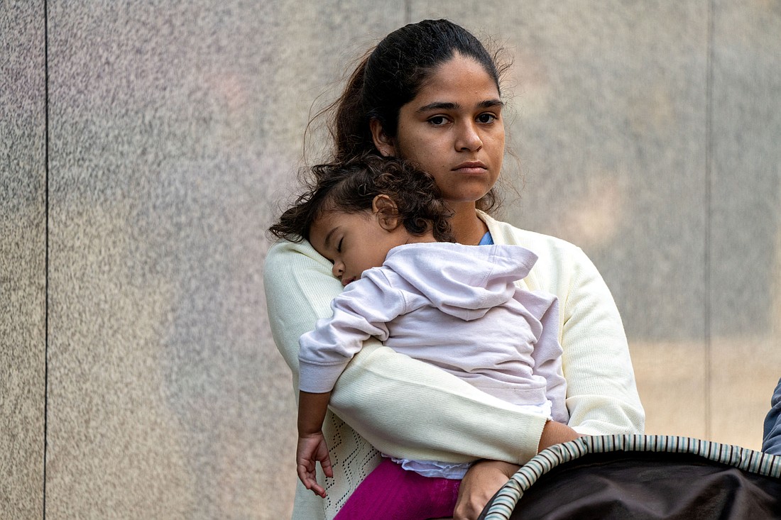 A migrant and her daughter wait for aid outside the offices of Catholic Charities in New York City Aug. 16, 2022.