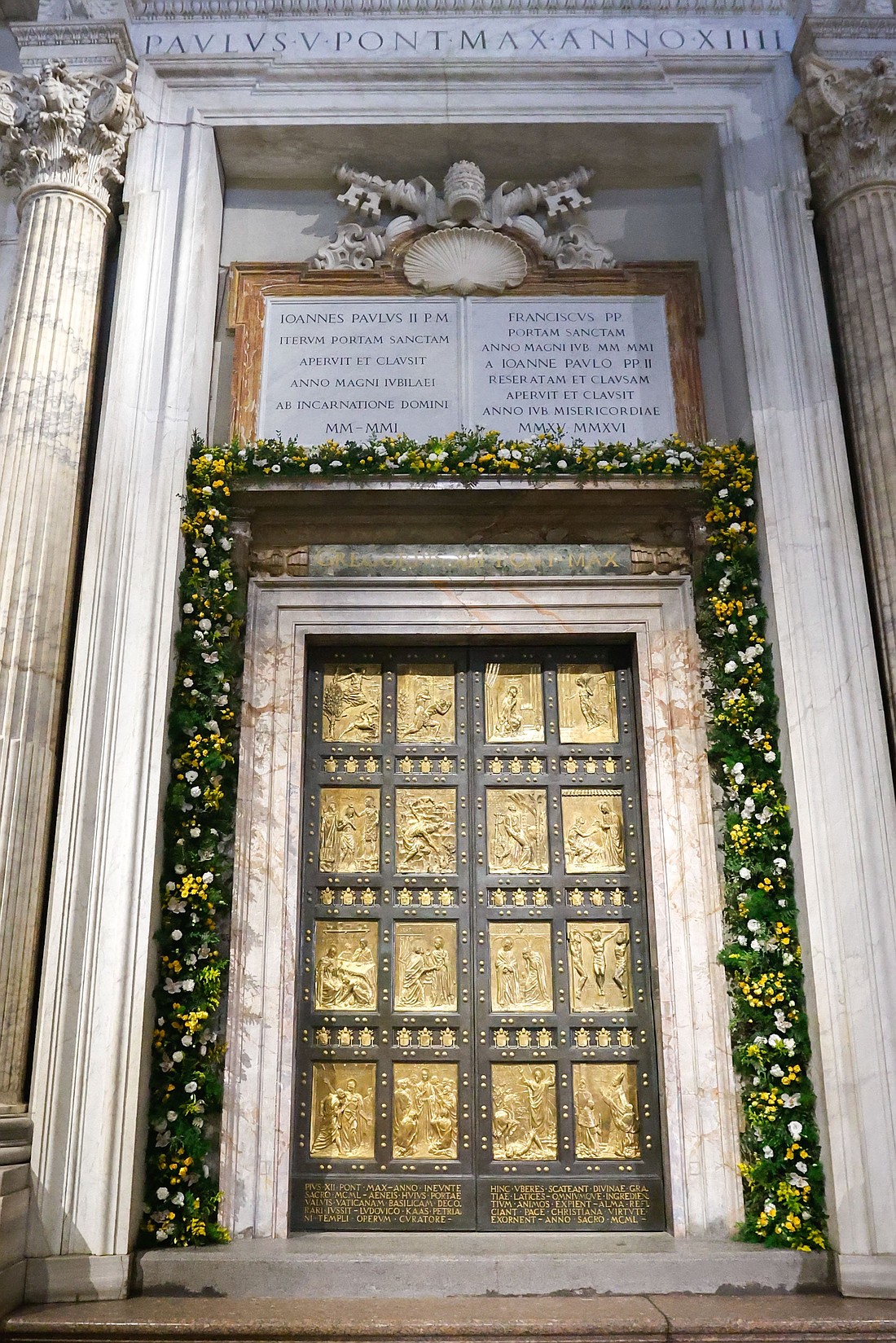 The Holy Door of St. Peter’s Basilica at the Vatican is adorned with flowers in this file photo from May 9, 2024. The Vatican announced Nov. 25 that a webcam will be installed above the door for the Holy Year 2025. (CNS photo/Lola Gomez)