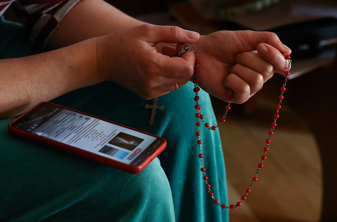 A Ukrainian woman who fled Russia's invasion of Ukraine prays with a rosary and prayers on her mobile phone in Lubaczow, Poland, March 21, 2022. (OSV News photo/Kacper Pempel, Reuters)