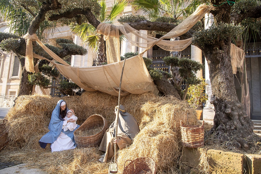 The people playing Jesus, Mary and Joseph in a living Nativity scene sit under an awning on the steps of Rome's Basilica of St. Mary Major Dec. 14, 2024. (CNS photo/Pablo Esparza)