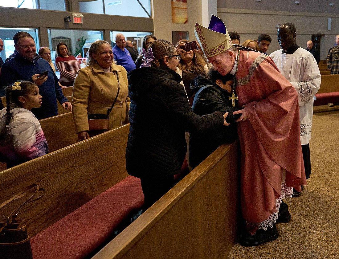 Bishop O'Connell greets a young man who attended the Sensory-Friendly Mass in St. Robert Bellarmine Co-Cathedral, Freehold. Vic Mistretta photo	D