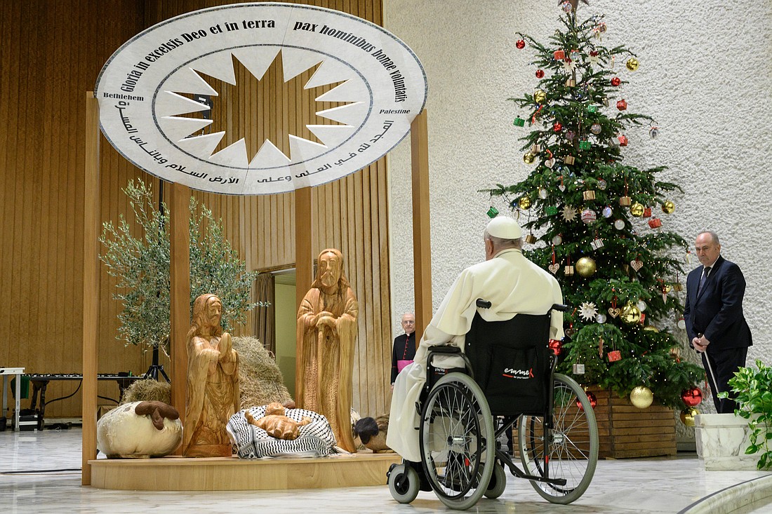 Pope Francis stops to pray in front of a Nativity scene from Bethlehem in the Vatican audience hall Dec. 7, 2024. The baby Jesus is lying on a white and black kaffiyeh, a Palestinian headdress. Around the star, written in Arabic and Latin, are the words of the angels: "Glory to God in the highest and on earth peace to people of good will." (CNS photo/Vatican Media)