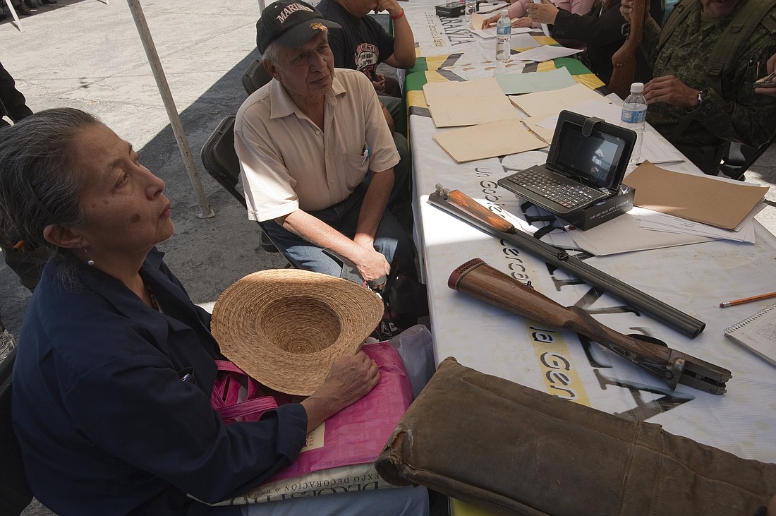 A man and woman sit near weapons during a gun buyback program outside Holy Kings Church in the Venustiano Carranza borough of Mexico City. The Mexican bishops' conference said in a Dec. 18, 2024, post on X that parishes would open their doors "so that people can voluntarily and safely hand over weapons" in coordination with the federal government. (OSV News photo/Keith Dannemiller)
