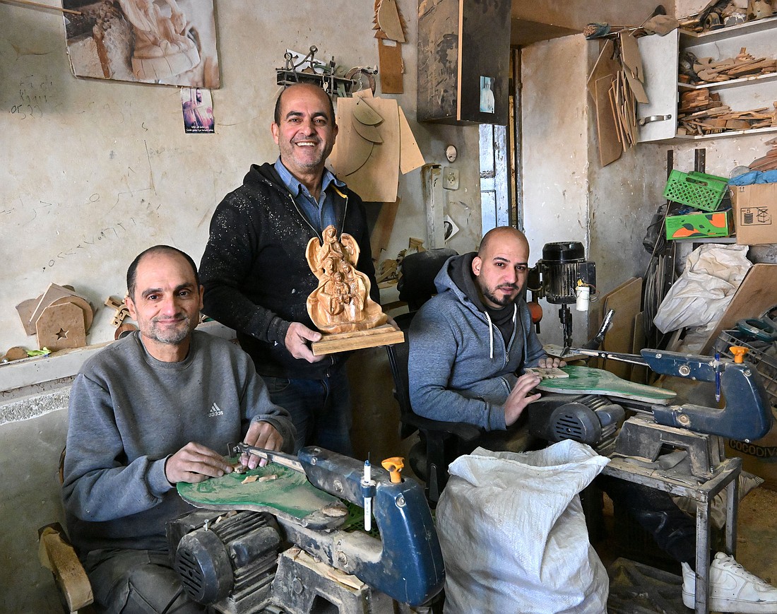 Ashraf Jarayseh, 60, center, stands with his brother, Elias, 52, left and his son, Majd, 27, in the family's Holy Family Co., in Beit Sahour, near Bethlehem, West Bank, Dec. 18, 2024. The company, which was founded by his grandfather, is among the best known for its handcrafted statues, creches, Christmas tree ornaments and crucifixes -- each piece made by hand on machines by a member of the family -- either Jarayseh himself, his brother or sons. (OSV News photo/Debbie Hill)