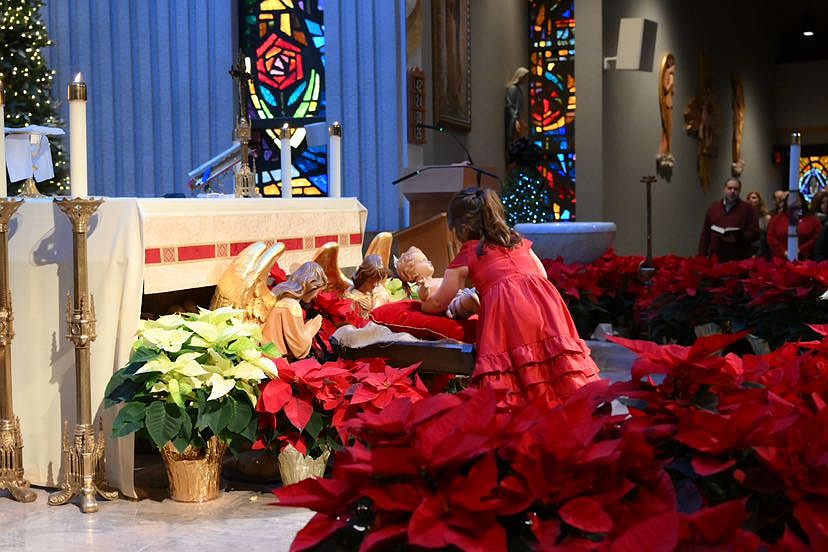 A young parishioner places an image of the Christ Child in the manger in St. Thomas More Church, Manalapan. Mike Ehrmann photo