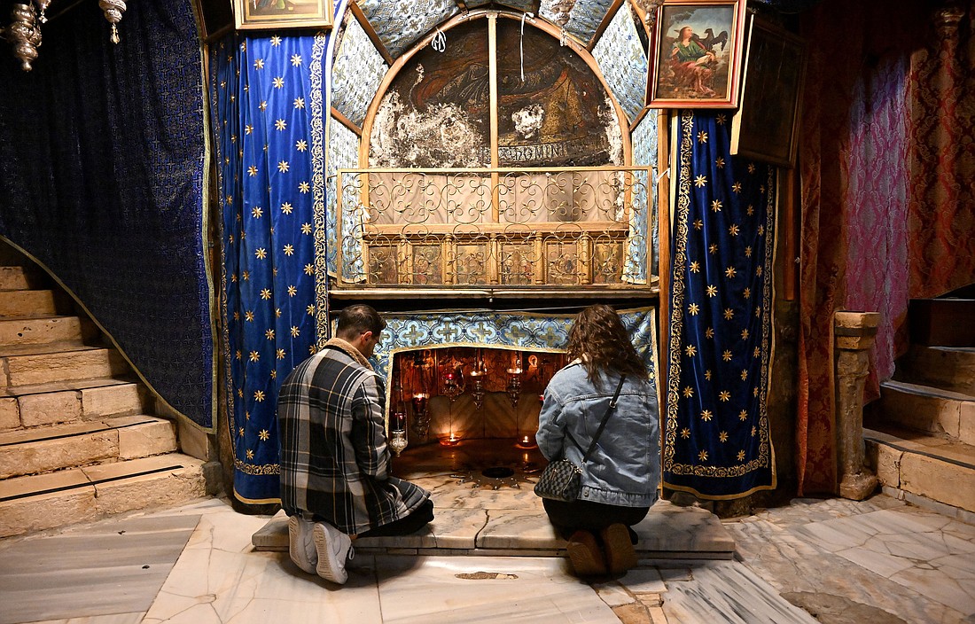 Palestinian Christians Alek Kahkejian, 25, and Joy Kharoufeh, 21, pray in the grotto of the Church of the Nativity, in Bethlehem, West Bank, Dec. 17, 2024, believed to be the site of the birth of Christ. The town of Bethlehem is empty of tourists before Christmas as the Israel-Hamas war is in its 14th month. (OSV News photo/Debbie Hill)