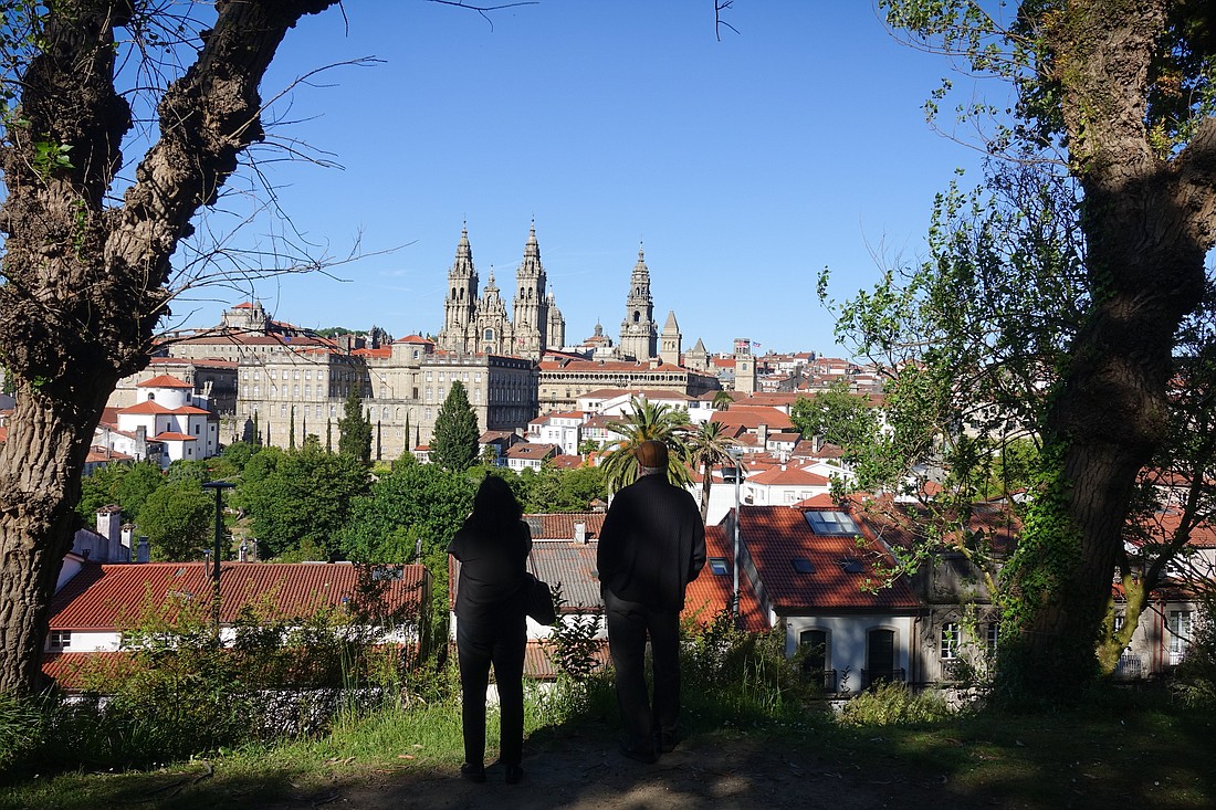 A woman and a man stand in a quiet city park May 29, 2024, and look at the cathedral in Santiago de Compostela in Spain. According to the pilgrims' office there, a record 499,239 pilgrims from all over the world walked Spain's famed Camino de Santiago in 2024. (OSV News photo/Andreas Drouve, KNA)