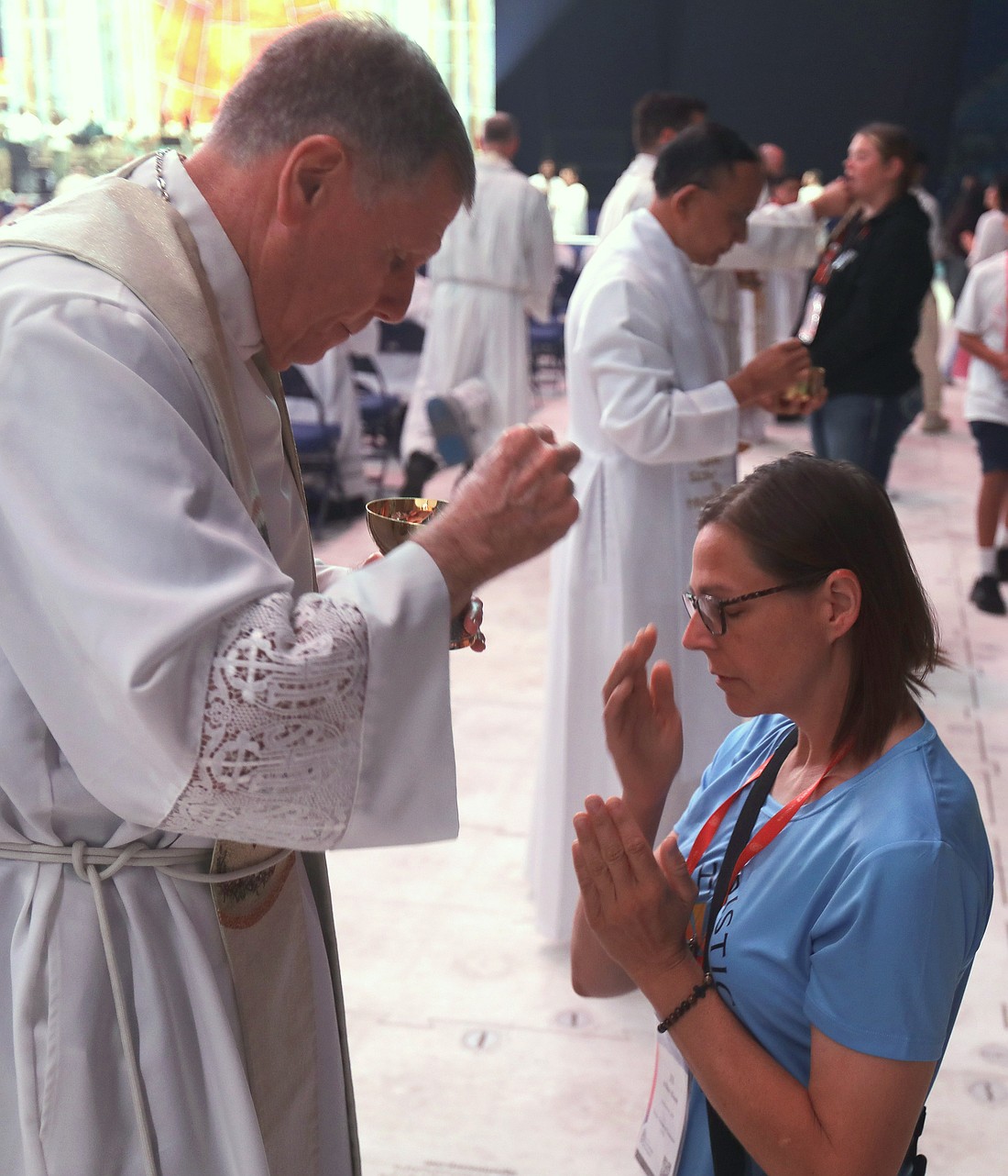 A pilgrim crosses herself after receiving Communion while kneeling during Holy Qurbana July 20, 2024, at Lucas Oil Stadium in Indianapolis during the National Eucharistic Congress. Holy Qurbana is the name for Mass in the Catholic Church's Syro-Malabar rite. (OSV News photo/Bob Roller)