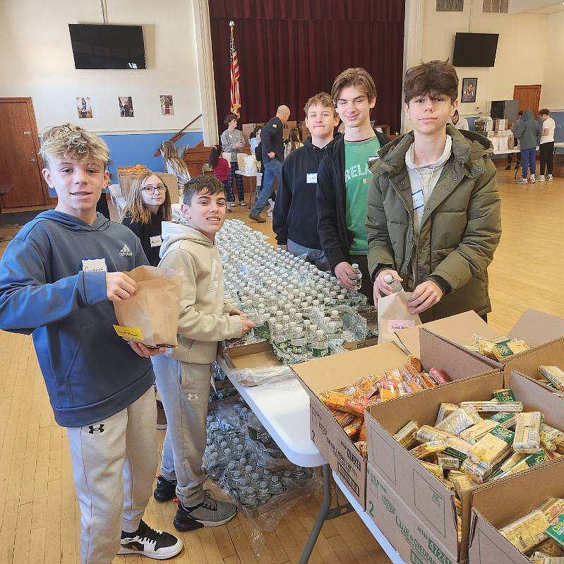 Young parishioners of St. Mary of the Lakes Parish, Medford, work together to assemble bags of food for agencies that assist people in need. Courtesy photo