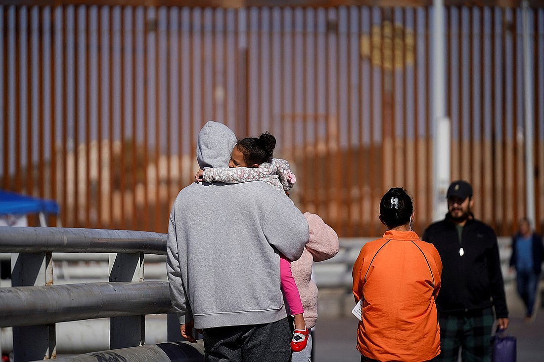 Una familia de inmigrantes cubanos camina con otros inmigrantes cerca de la valla fronteriza en Mexicali, México, después de que se cancelara su cita de asilo el 20 de enero de 2025. Foto de OSV News/Víctor Medina, Reuters