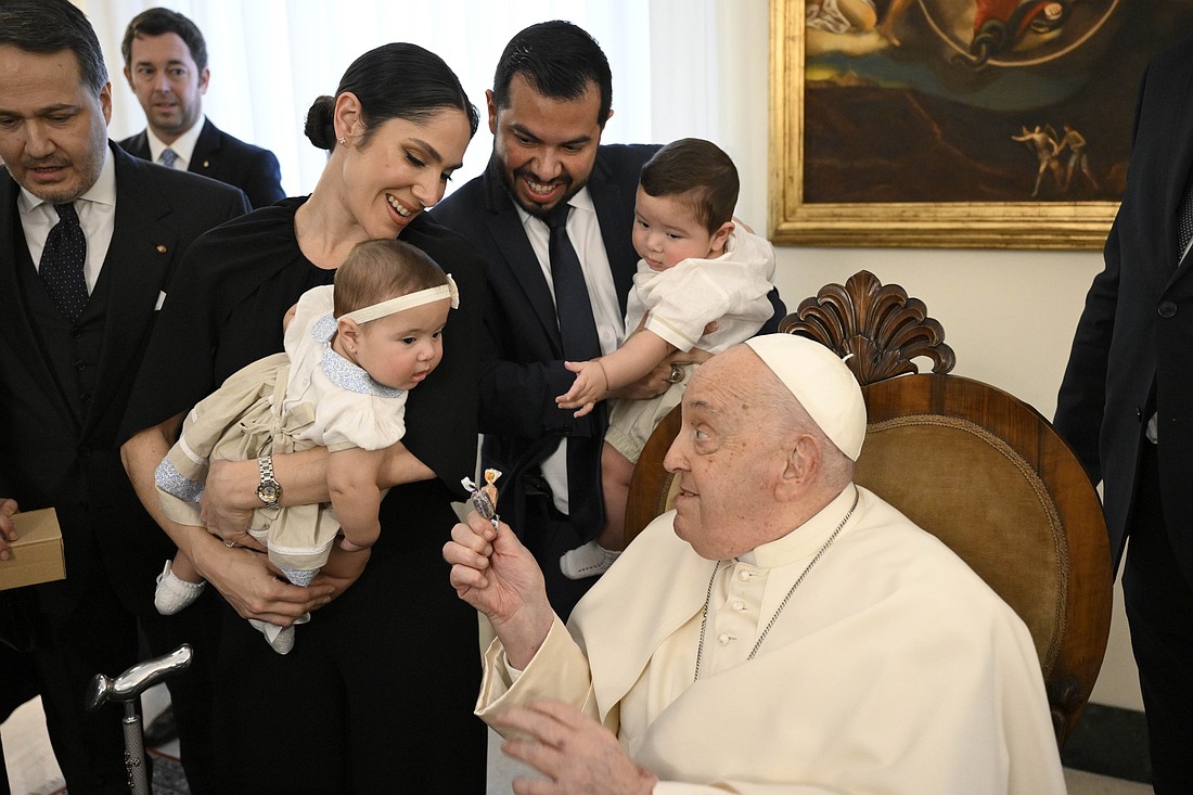 Pope Francis hands candy to a child at the end of a meeting with members of the Spanish "Gaudium et Spes" Foundation at his residence, the Domus Sanctae Marthae, before checking into Rome's Gemelli hospital Feb. 14, 2025, for tests and treatment of bronchitis. (CNS photo/Vatican Media)