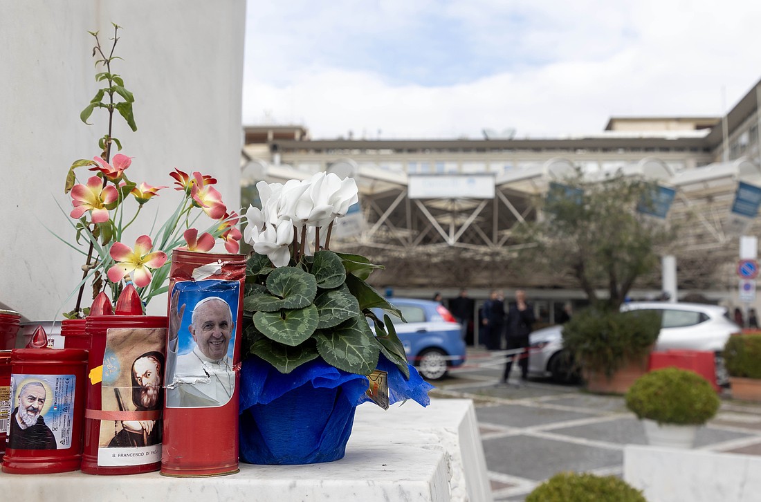 Flowers and votive candles sit at the base of a statue of St. John Paul II outside Rome's Gemelli hospital Feb. 18, 2025, where Pope Francis is a patient. (CNS photo/Pablo Esparza)