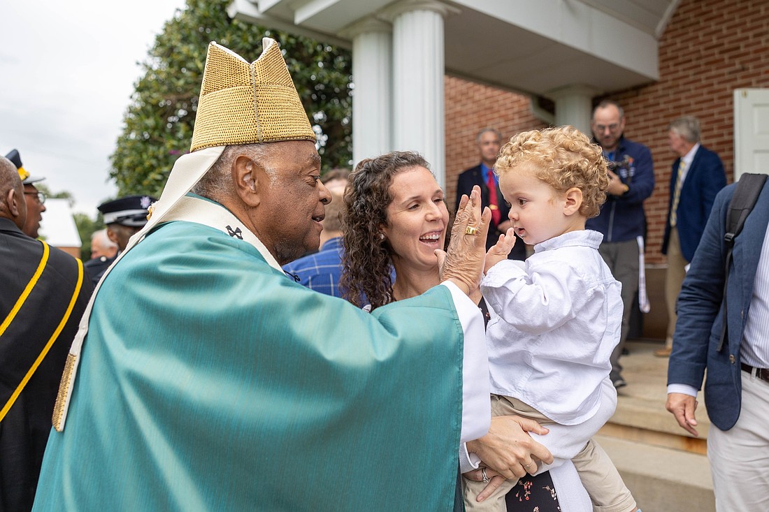 After celebrating a 350th anniversary Mass for St. Mary Parish in Newport, Md., on Sept. 7, 2024, Washington Cardinal Wilton D. Gregory greets parishioners outside the church and plays Patty-Cake with a little boy, Gregory Skibinsky, held by his mother, Erica Skibinsky. (OSV News photo/Mihoko Owada, Catholic Standard)