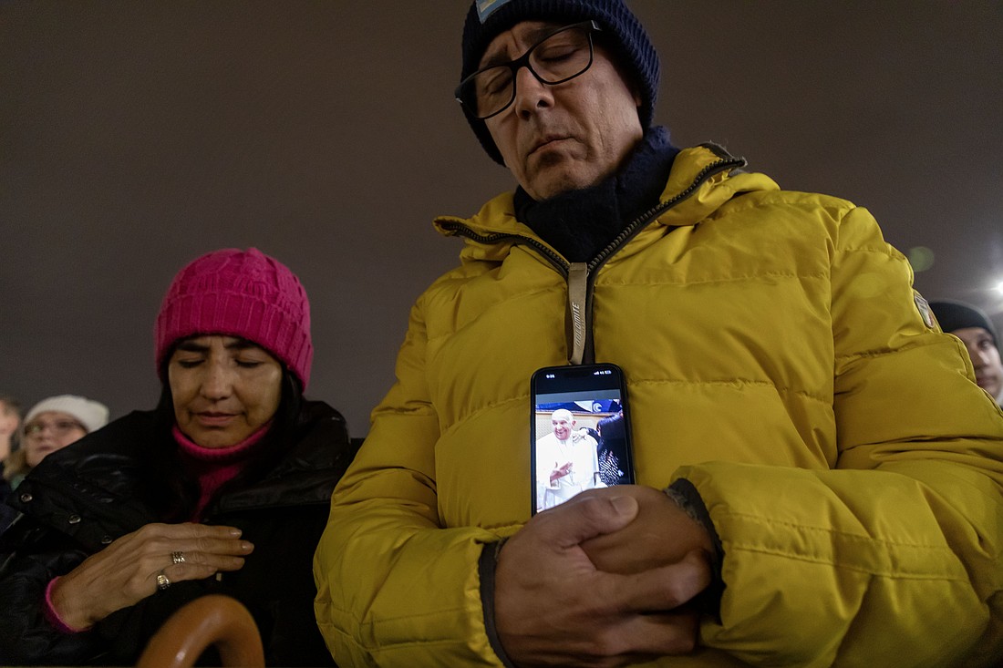 Un hombre sostiene su teléfono mostrando una imagen del Papa Francisco mientras se une al cardenal Pietro Parolin, secretario de estado del Vaticano, para rezar el rosario por el Papa en la Plaza de San Pedro en el Vaticano el 24 de febrero de 2025. Cardenales residentes en Roma, líderes de la Curia Romana y fieles se unieron a la oración nocturna. (Foto CNS/Pablo Esparza)