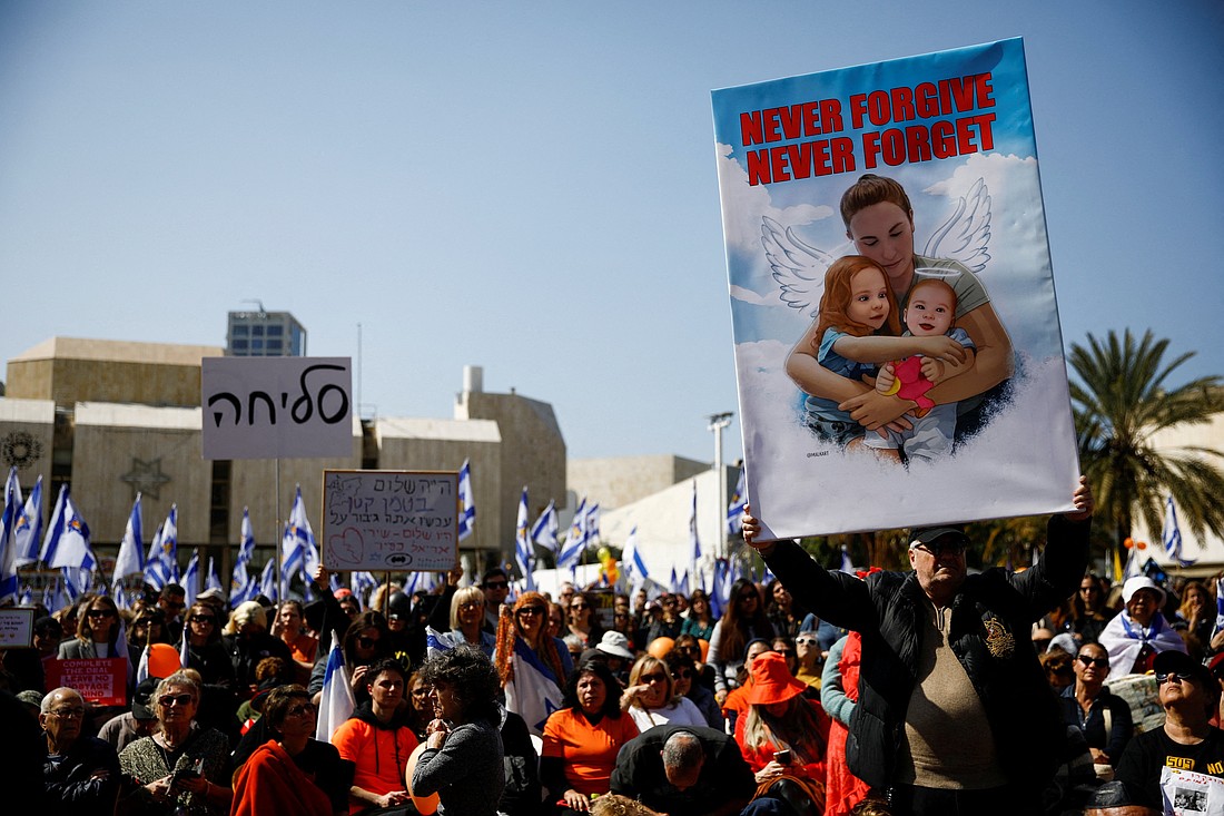 A man holds up a poster of Shiri Bibas, 32, and her two children, Kfir, 9 months old, and Ariel, 4, as Israelis gather at a public square dedicated to hostages in Tel Aviv, Israel, Feb. 26, 2025, on the day of a funeral procession for the Bibas family. They were kidnapped from their home in Nir Oz Kibbutz during Hamas' deadly Oct. 7, 2023, attack and then killed in Gaza by their captors. (OSV News photo/Shir Torem, Reuters)