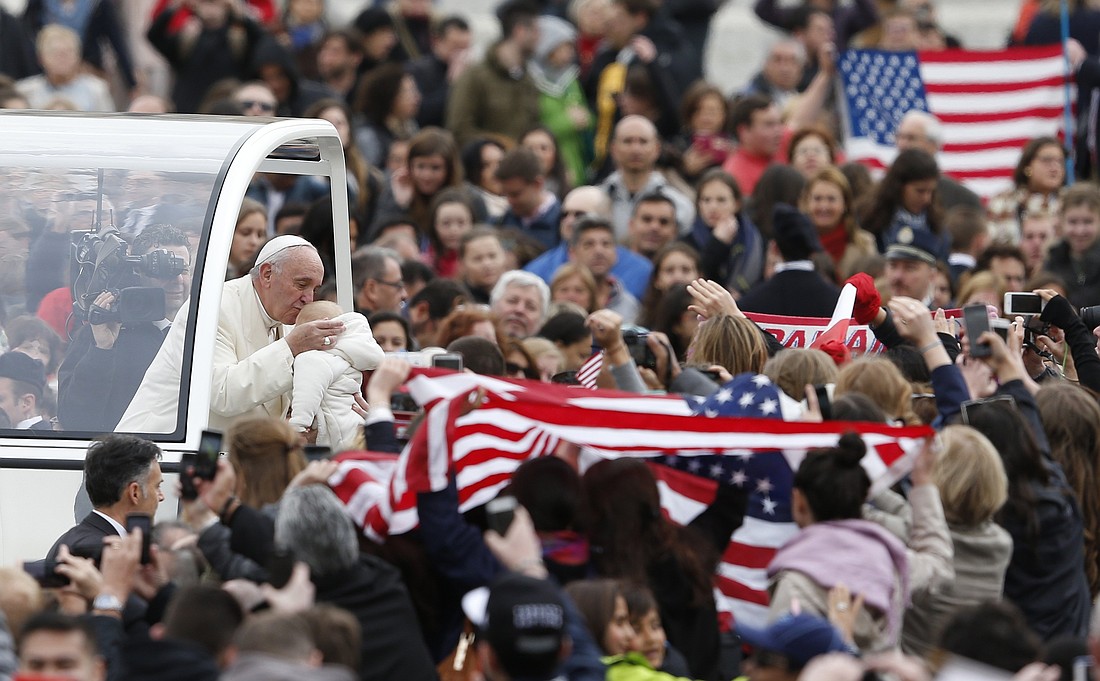 U.S. flags are seen as Pope Francis kisses a baby during his general audience in St. Peter's Square at the Vatican March 23, 2016. Multiple Pew Research surveys show that the pope has been "broadly popular" among U.S. Catholics throughout his papacy. The latest survey was conducted by phone Feb. 3-9, 2025. (CNS photo/Paul Haring)