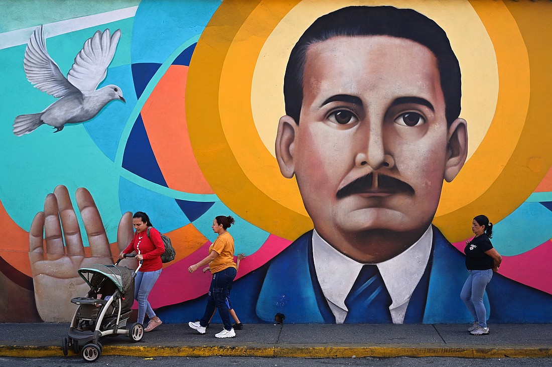 Women and children pass by a mural of of Blessed José Gregorio Hernández, known as the "Doctor of the Poor," in Caracas, Venezuela, Feb. 25, 2025. On Feb. 24, while continuing treatment for double pneumonia at Rome's Gemelli Hospital, Pope Francis approved  the Dicastery for the Causes of Saints' decision on his canonizaton, making the doctor the Caribbean nation's first saint. (OSV News photo/Gaby Oraa, Reuters)