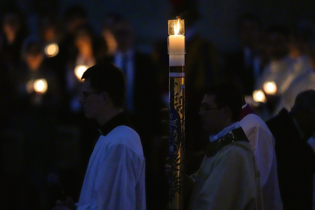 Deacon Nicholas Monnin, a seminarian from the Diocese of Fort Wayne–South Bend studying at the Pontifical North American College in Rome, carries the paschal candle during the entrance procession of Easter Vigil Mass in St. Peter’s Basilica at the Vatican April 19, 2025. (CNS photo/Lola Gomez)