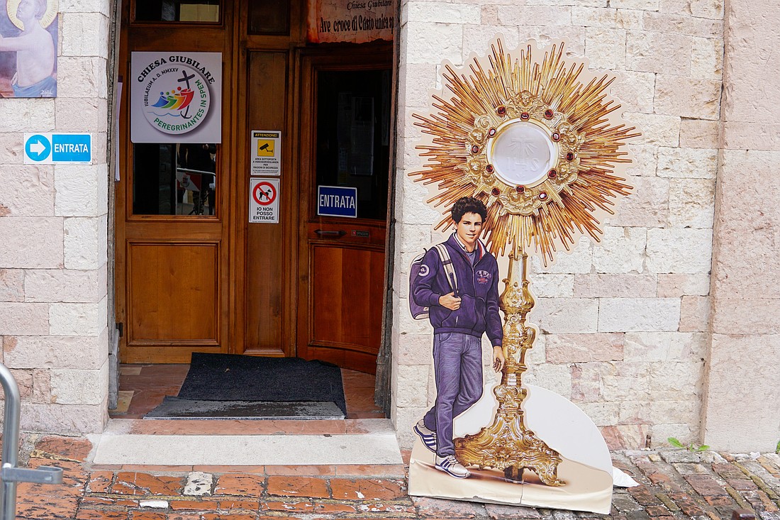 A sign featuring Blessed Carlo Acutis stands outside the Church of St. Mary Major in Assisi, Italy, April 1, 2025. (CNS photo/Justin McLellan)