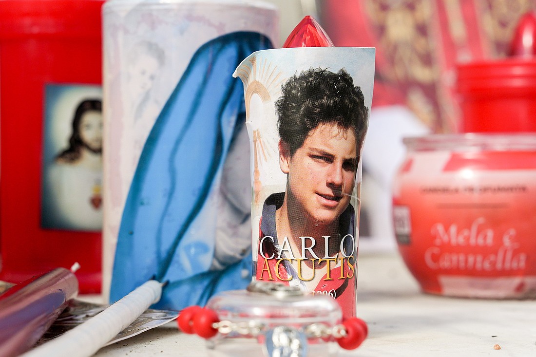 Votive candles and religious images, including one of Blessed Carlo Acutis, are seen at the base of a statue of St. John Paul II outside Rome's Gemelli hospital Feb. 27, 2025, while Pope Francis was being treated there for double pneumonia. (CNS photo/Lola Gomez)