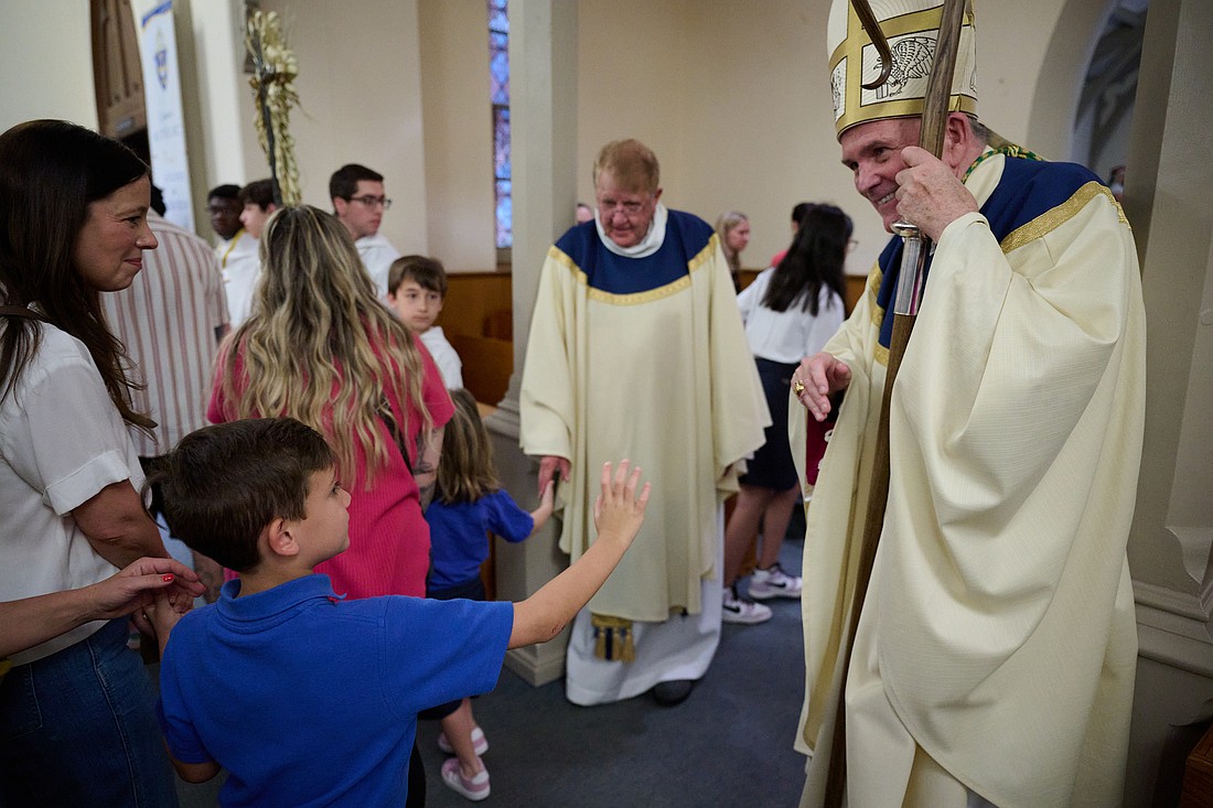As part of his greeting to Bishop O'Connell, a St. Rose of Lima School student gets ready to give the Bishop a "high five." At left, Father James Conover, pastor of St. Rose of Lima Parish, also greets his flock. Mike Ehrmann photo