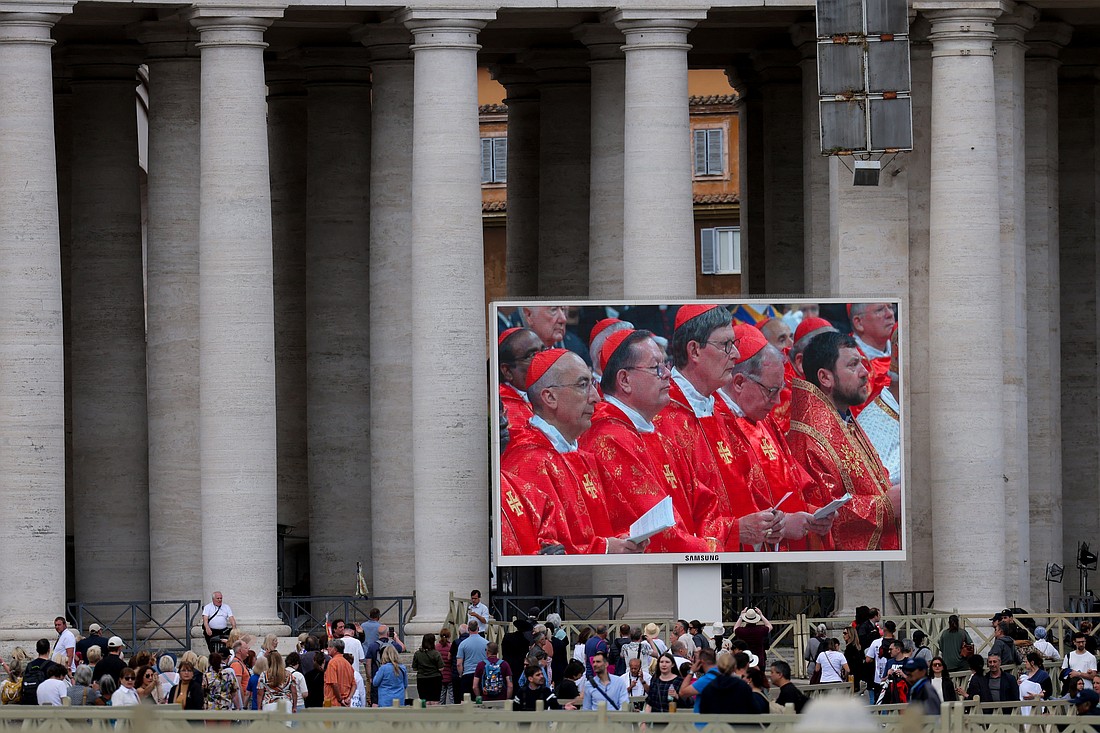People watch on a large screen as cardinals attend a Mass in St. Peter's Basilica at the Vatican, May 7, 2025, the first day of the conclave to elect a new pope. (OSV News photo/Kevin Coombs, Reuters)