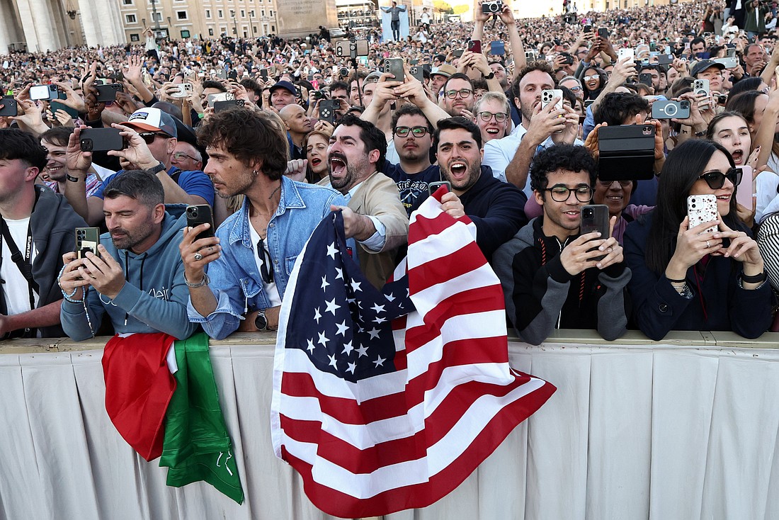 Men wave a U.S. flag as Cardinal Robert Francis Prevost, who has chosen the papal name Leo XIV, appears on the central balcony of St. Peter's Basilica at the Vatican May 8, 2025, following his election during the conclave. He is the first American pope in history. (OSV News photo/Eloisa Lopez, Reuters)