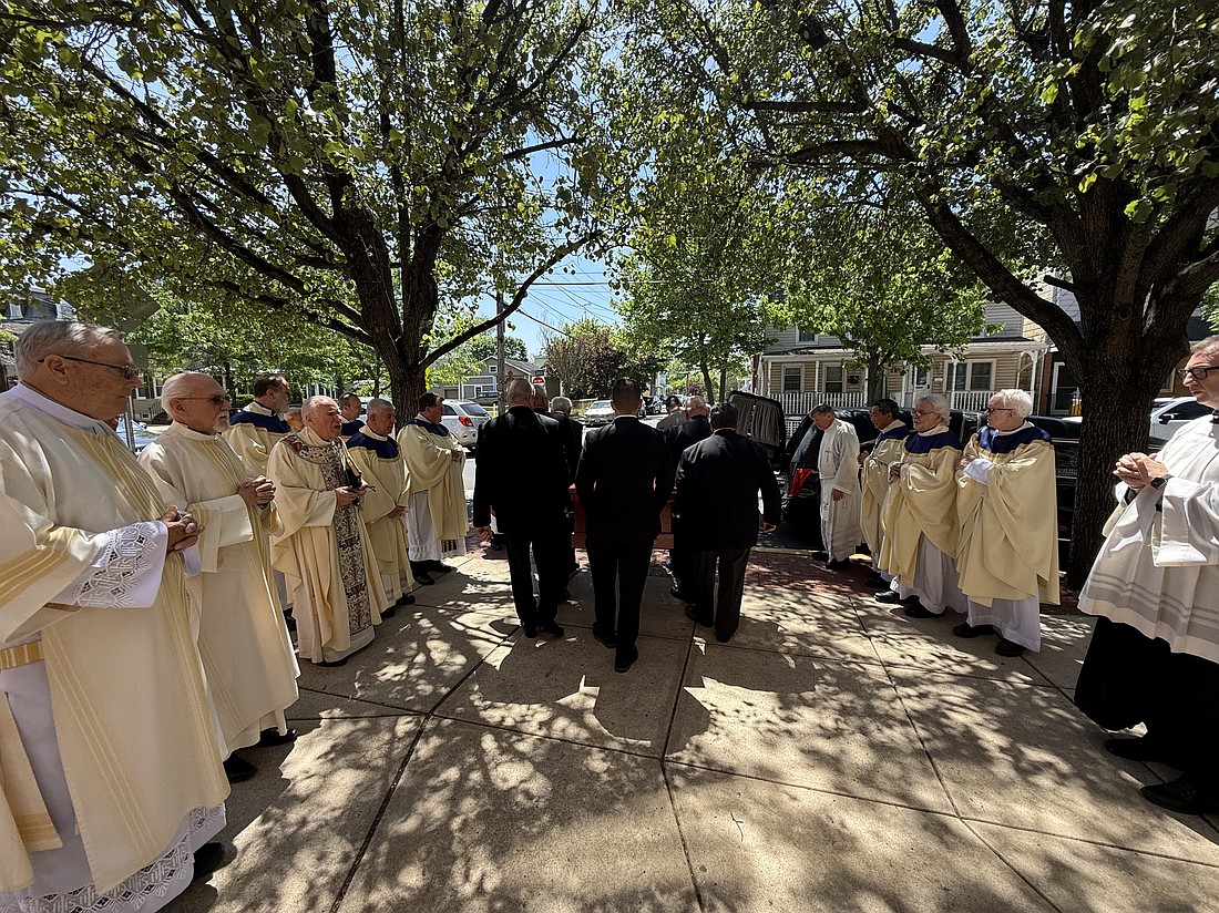 The priests in attendance sing Salve Regina as Father Felix Venza’s casket leaves St. Mary’s Church May 12.