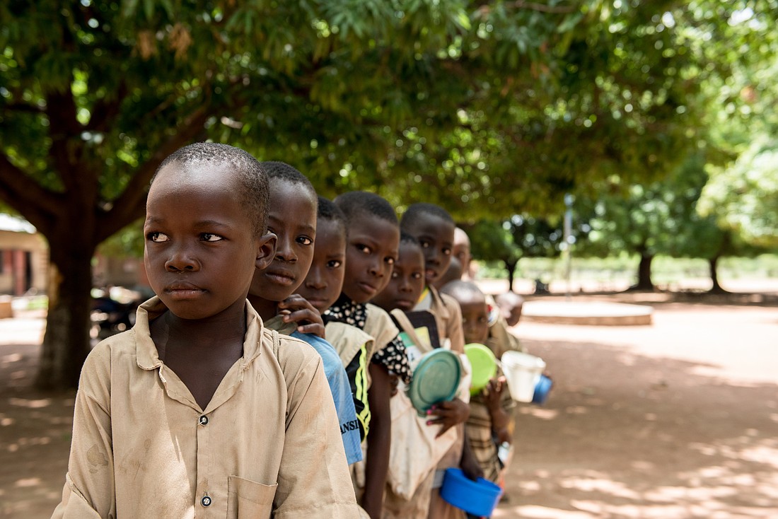 Students at a school in Kandi, Benin, are pictured in a file photo lining up as parent volunteers prepare and serve warm, nutritious meals for students each school day under a Catholic Relief Services' program called Food for Education. The program is supported by the McGovern-Dole International Food for Education and Child Nutrition initiative sponsored and funded by the U.S. Department of Agriculture and is run in partnership with local organizations. (OSV News photo/Michael Stulman, Catholic Relief Services)..